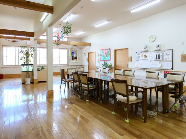 木目調の床のダイニングルーム 娯楽室 明るく広々とした空間でゆったりとした食事が楽しめます。木の温もりが感じられる家具が並んでいます。