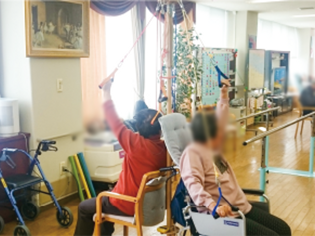 健康づくりの場 機能訓練室 自然光が差し込む明るい空間で、入居者の方々がリハビリに取り組んでいらっしゃいます。