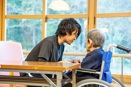 車椅子の高齢者と介護士の会話