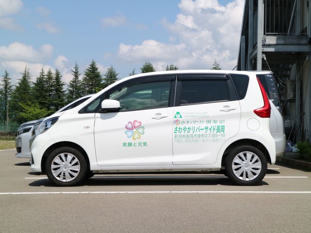 白いサービス車両と建物 社用車 清潔感のあふれる白いサービス車両が停まっており、日々の業務を支える一面です。