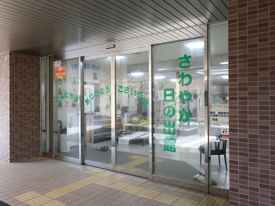 玄関の自動扉の部分に、感謝の言葉が緑色の文字で表示されている。その右側のガラスには、施設名称が縦書きされている。