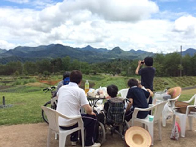 自然を楽しむ風景 庭 青空の下、みなさんがのんびりとした時間を過ごしています。庭から眺める山々が美しいです。
