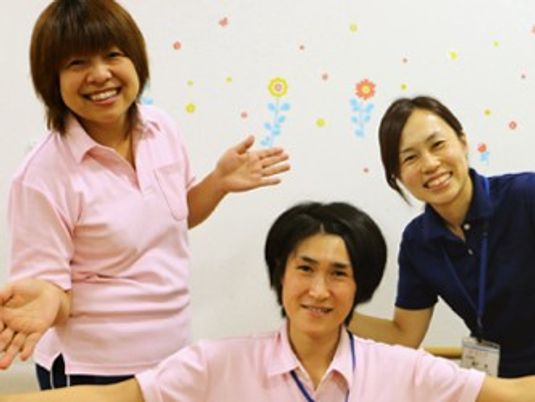 スタッフが笑顔で並ぶ室内  
