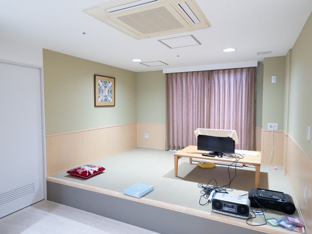 和風の明るい居室 居室 天井が高く落ち着いた色合いの部屋で、中央にはテーブルとテレビが置かれています。