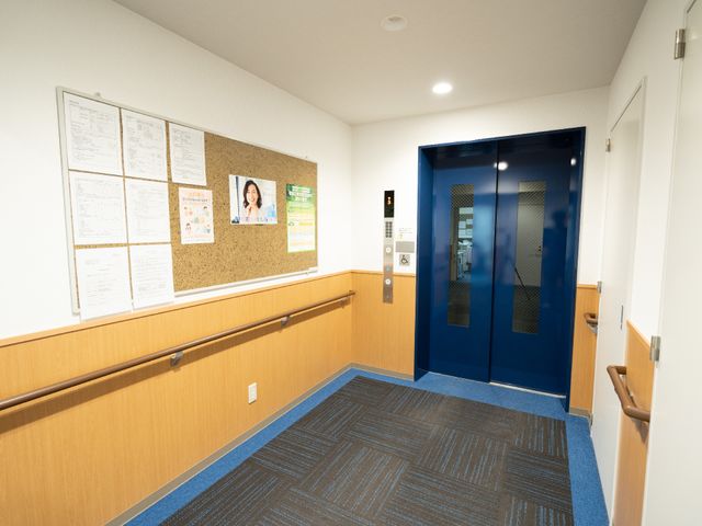 明るいエレベーターホール エレベーター 清潔感があり、情報掲示板が備え付けられた通路です。明確な案内表示で安心です。