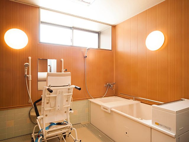 バスタブと介護用椅子のある浴室 浴室 自然光が差し込む明るい空間で、介護用椅子が備え付けられており、安心して利用できます。