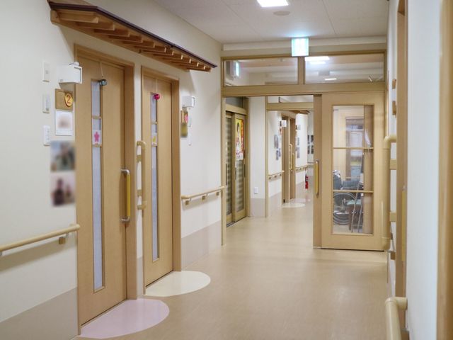 清潔な廊下と部屋の入口 廊下 手すり付きで明るい廊下が、利用者の快適な移動を支えます。安全とゆとりが感じられる設計です。
