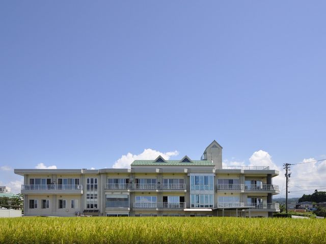 外観の建物 外観   青空の下に、バルコニー付きの建物が広がっています。周囲にのどかな田畑が見え、落ち着いた環境です。