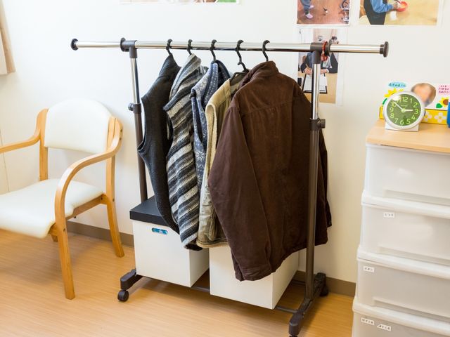 コートラックと椅子のある部屋 居室 整頓された居室には、コートをかけるスペースや休憩できる椅子が設けられ、快適な個人の空間が保たれています。