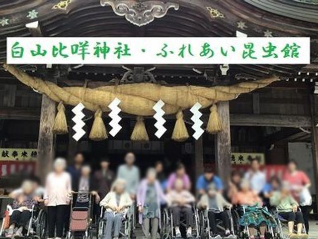 看板の前に集まる人々 看板 施設の看板前で、交流を楽しむスタッフと利用者の様子が伺えます。温かい雰囲気が魅力です。