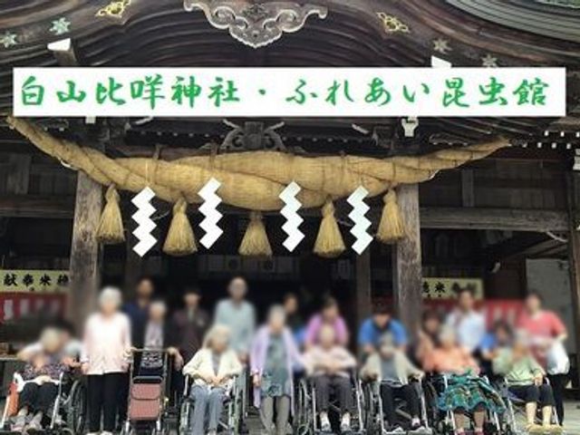 看板の前に集まる人々 看板 施設の看板前で、交流を楽しむスタッフと利用者の様子が伺えます。温かい雰囲気が魅力です。