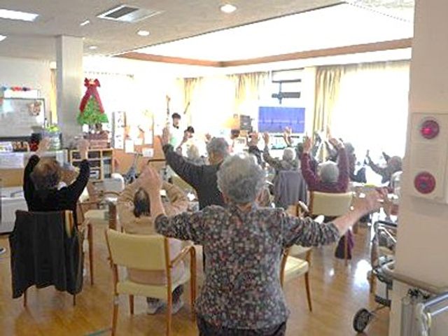 アクティビティを楽しむリビング リビング 明るい空間で、入居者の方々が楽しくアクティビティに参加しています。自然光が心地よさを提供します。