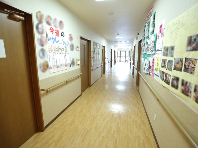 廊下の壁に掲示物 廊下 壁には色とりどりの掲示物が飾られ、温かみのある廊下が広がっており、くつろいだ雰囲気を肌で感じられます。車椅子ユーザーにも安心な幅広の通路が特徴です。