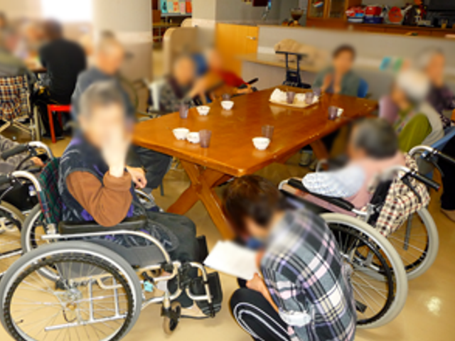 明るい共有スペース リビング 車椅子の方々が集まり楽しく会話をしている様子です。温かみのある空間で憩えます。