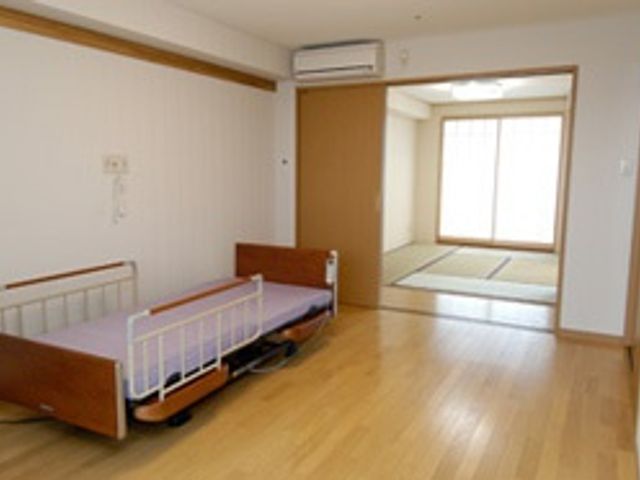 広々とした居室 居室 明るい自然光が差し込む、快適な居住空間です。温かみのある木製ベッドが配置されています。