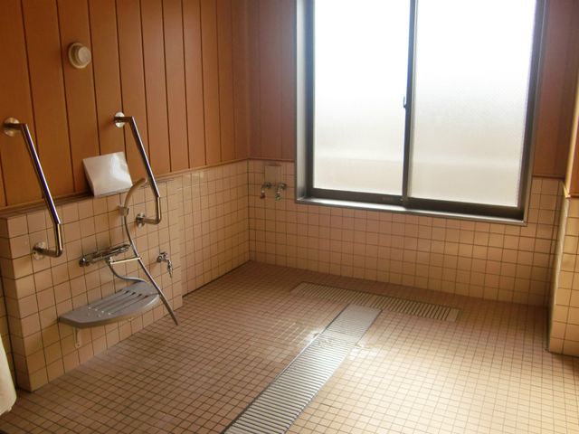 手すり付きの洗面所 浴室 明るい光が差し込む、安全支持具が備わった洗い場です。利用者の安心を考えた設計になっています。