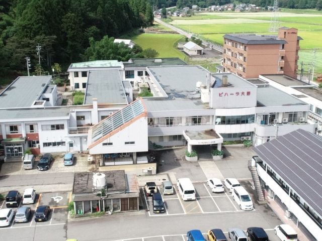 広い駐車場のある建物 外観 自然に囲まれた場所に位置し、広々とした駐車スペースがあります。緑豊かな環境で働けます。