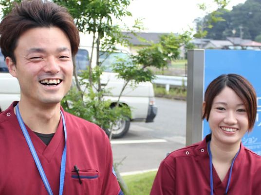 笑顔の職員が立つ外観  