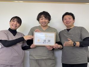 スタッフ3人が賞状を持つ室内  