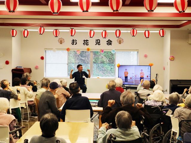 明るいイベント会場 リビング 自然光が差し込むイベント会場で、入居者の方々が楽しく交流されています。華やかな装飾が雰囲気を盛り上げます。