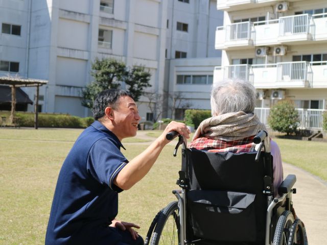 笑顔で話す人々の庭 庭   広々とした庭で、親しみやすいスタッフが利用者と穏やかな時間を過ごしています。