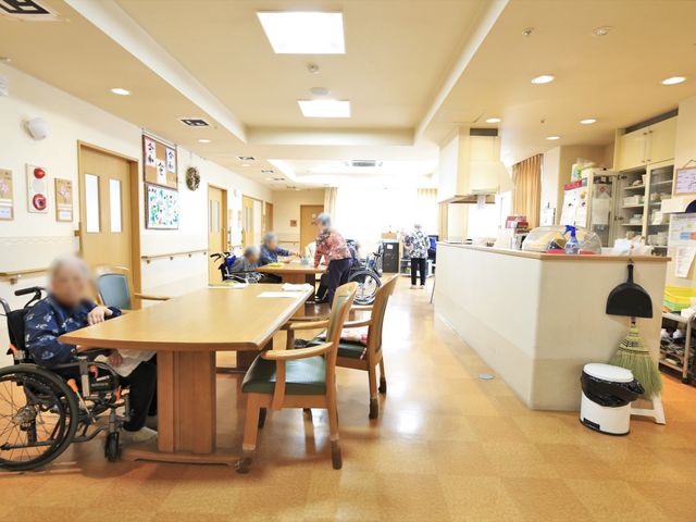 共有スペースでの日常風景 共有スペース ゆったりとしたスペースが広がる、明るく温かみのある食事の場所です。利用者の方々がくつろいで日々の食事を楽しんでいます。