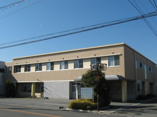 日中の明るい施設外観 外観 ゆったりとした造りの建物前には、緑が植えられており、訪れる人を温かく迎えています。