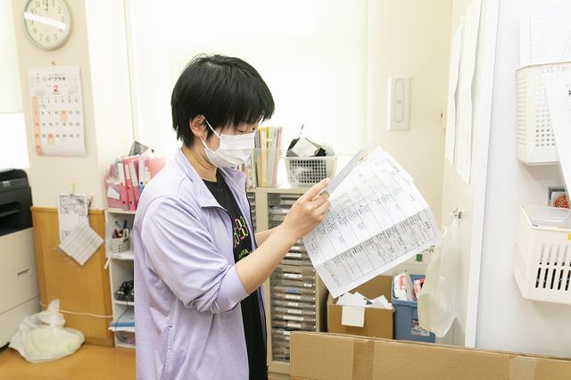 細かい作業をするスタッフ スタッフイメージ 資料を確認するスタッフの忙しい姿です。働く環境の一部が垣間見えます。