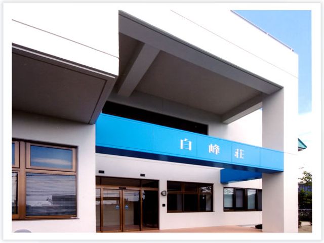 青い看板の建物の外観 外観 広い屋根が印象的な場所です。明るい空間が広がり、訪れる人を迎え入れます。
