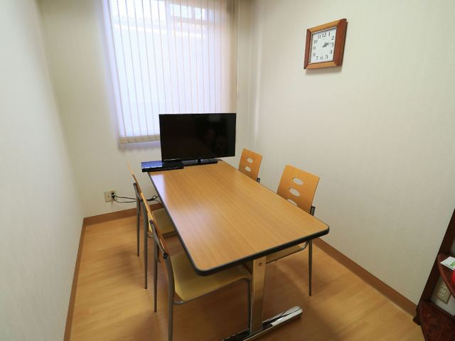 プライベートな居室 談話室 ゆったりとしたテーブルとチェアが配置されており、個々の空間で静かに過ごすことができます。壁掛けの時計が時間を知らせ、日常生活をサポートしています。
