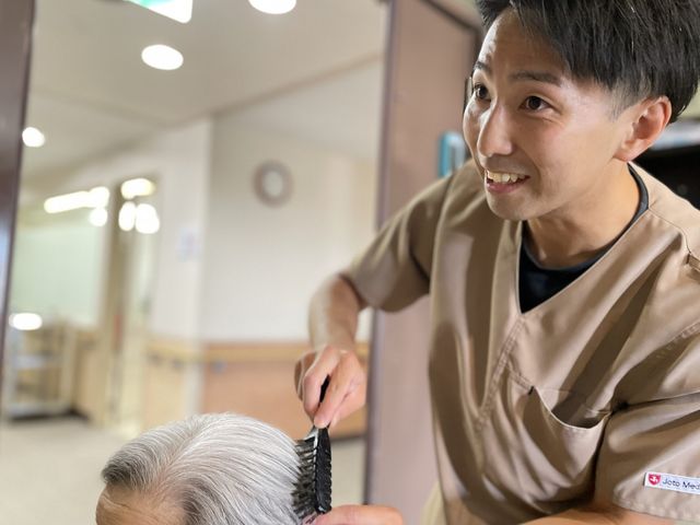 髪を整える様子 スタッフイメージ スタッフが利用者の髪を整えています。明るく親しみやすい雰囲気が特徴です。