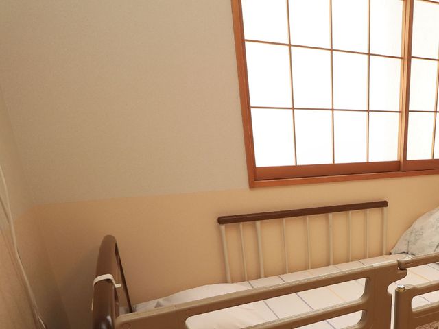 和やかな居室の一角 居室 陽光が差し込む落ち着いた雰囲気の部屋で、ゆったりとした時間が過ごせる空間です。手すりが整ったセーフティベッドが設置され、安全に配慮されています。