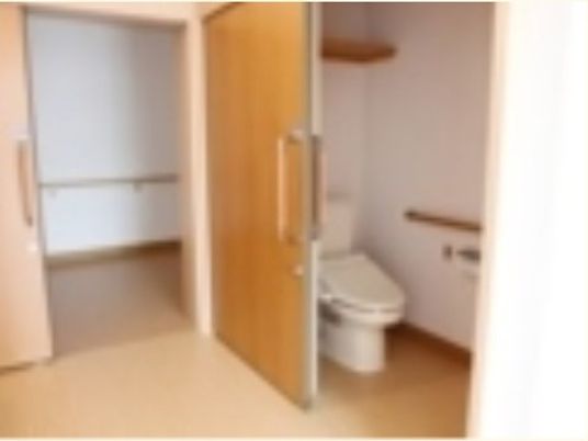 スローライフ山梨（介護専用型特定施設入居者生活介護）のトイレ。引き戸タイプの入り口で、床はオールフラット仕様になっている。