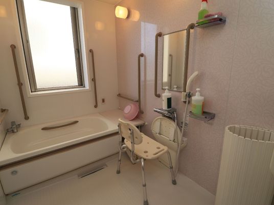 浴室内部は落ち着いたベージュ色を基調としている。壁には大きめの窓を設け、各所に複数の手すりを設置している。