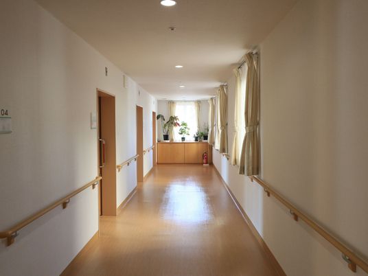 施設の写真 施設内の廊下は、白色とベージュ色のシンプルな内装となっている。左側には、入居者様の居室が３部屋並んでいる。