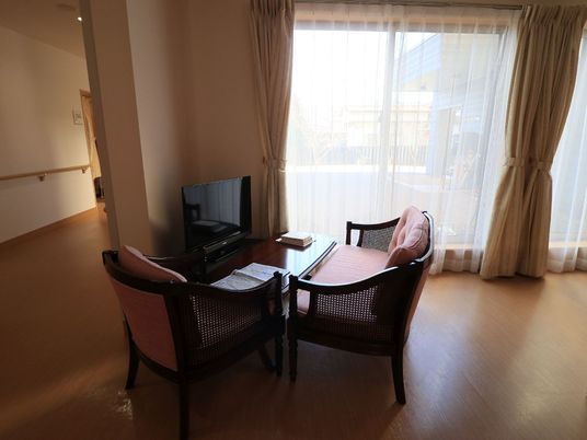 廊下の一角には、窓際に２脚の椅子とテーブルが並べられている。その向かいには、テレビも設置されている。