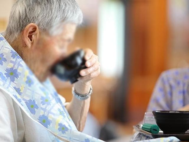食事中の入居者様 ダイニングルーム 落ち着いた雰囲気の中でお食事を楽しむことができ、職員によるサポートも充実しています。