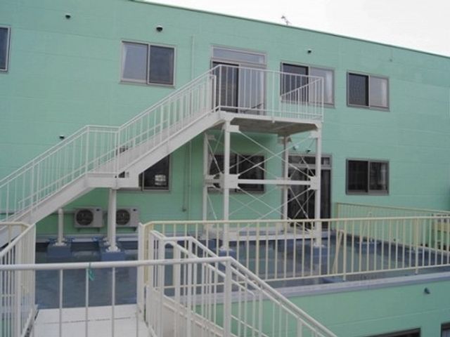 緑色の外壁と階段 施設外観 きれいに整備された階段が設けられた施設の外壁で、働く環境の安全性に配慮されています。