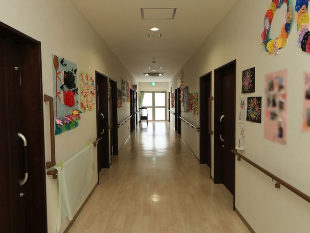 アートが飾られた廊下 通路 壁に手作りのアートが並び、居心地の良い温かみが感じられる通路です。利用者の作品展示により、日々の生活に色と活気を与えています。