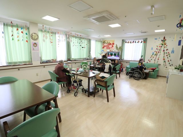 明るい共有スペース 共有スペース 広々とした食堂には、ゆったりとした座席が配され、休憩や交流の時間を楽しめる雰囲気です。窓辺ではソファーでくつろぐ人の姿もあります。
