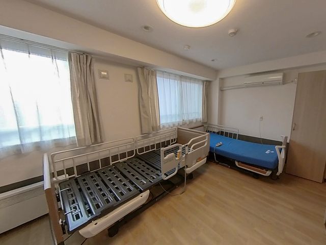 快適な居室の一角 居室 天井の照明が柔らかい光を放つ居室です。ベッドの配置がゆったりとしており、快適な個人スペースが確保されています。
