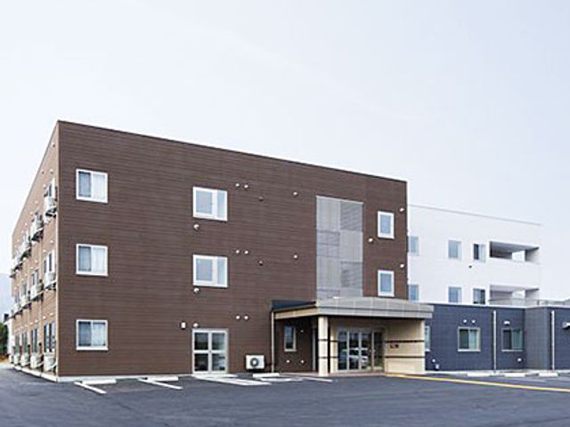 モダンな施設の外観 外観 落ち着いた色合いの建物で、広々とした駐車スペースが確保されています。
