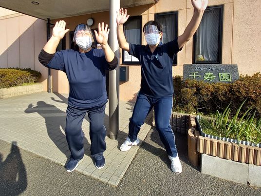 笑顔の職員が玄関前に立つ外観  