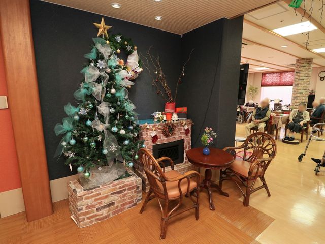 暖炉とクリスマスツリーのあるリビング 共有スペース ゆったりとした椅子が置かれたリビングには、季節感のあふれる装飾が施され、訪れる人々に安らぎを提供しています。
