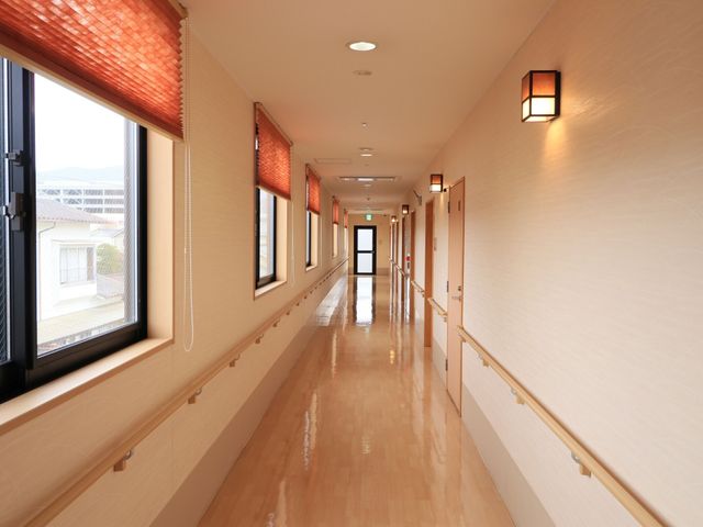 明るく広々とした廊下 通路 ゆったりとした通路は温かみのある照明で照らされ、どなたでも安心して歩けるよう手すりが備えられています。
