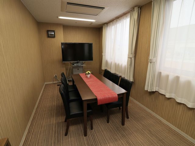 快適な居室のテーブルセット 共有スペース きれいに整えられた居室には四人掛けのテーブルが置かれ、壁掛けテレビで映画やドラマをお楽しみいただけます。