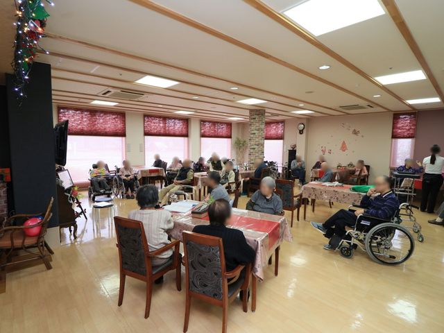 居心地の良い共有スペース ダイニング 明るく広々とした食堂では、利用者が集い憩える場が提供されています。椅子に座って、皆で交流を深めている様子が感じられます。