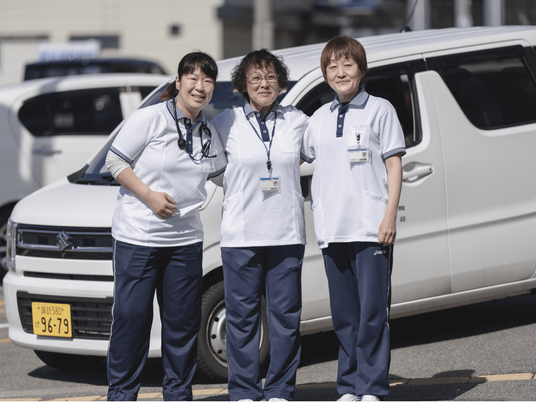送迎車の前のスタッフ  