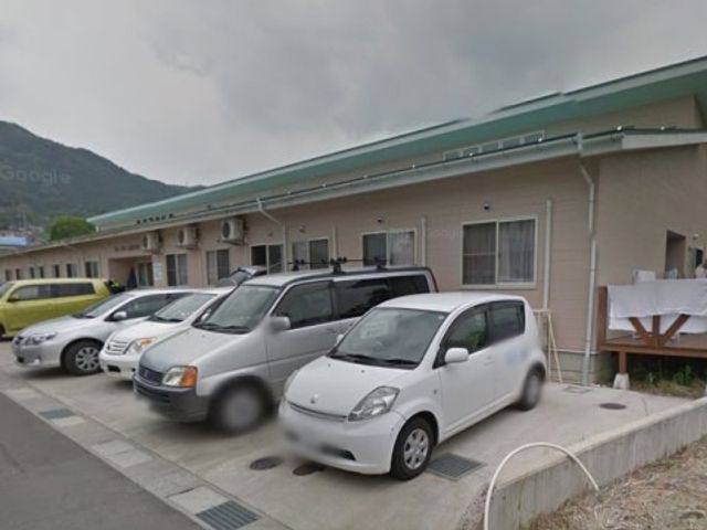 ベージュの壁の建物外観 駐車場 ベージュ色の建物が並ぶ、静かな雰囲気の敷地です。訪れる方々をやさしく迎える外観が印象的です。