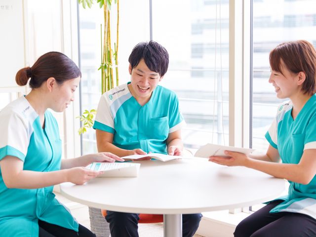 職員の交流風景 スタッフイメージ 自然光がたっぷり入る明るい空間で、和やかに職員同士のコミュニケーションが行われています。